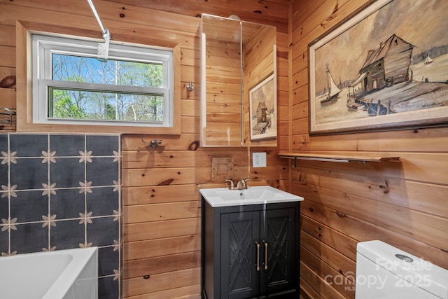 bathroom featuring wood walls, toilet, vanity, and a bathtub