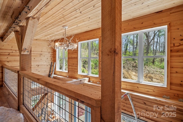 hall featuring a chandelier, wooden walls, wood-type flooring, and wood ceiling