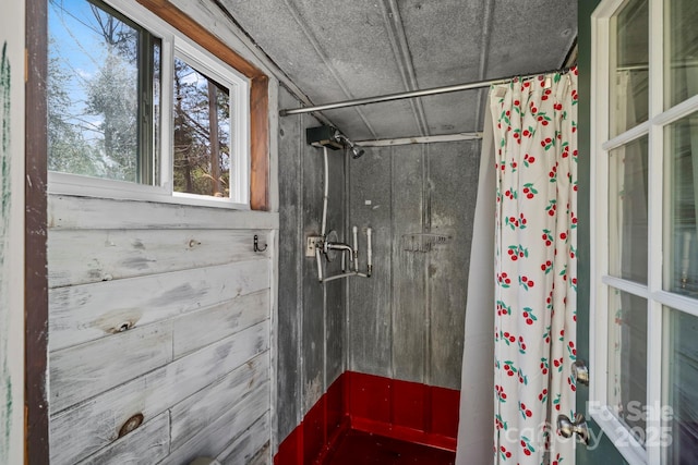 bathroom featuring a shower with shower curtain and wooden walls