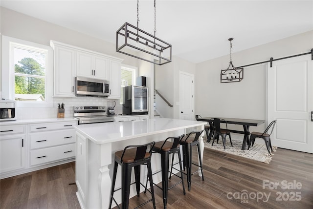 5028 Lewis Rd, Gastonia, NC 28052 - kitchen featuring appliances with stainless steel finishes, dark wood finished floors, decorative backsplash, a kitchen bar, and white cabinets