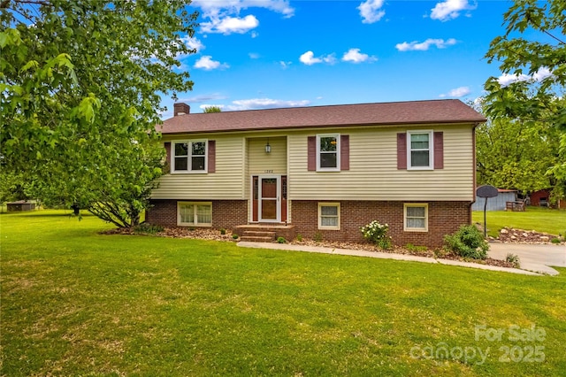 split foyer home featuring brick siding, a front yard, and a chimney