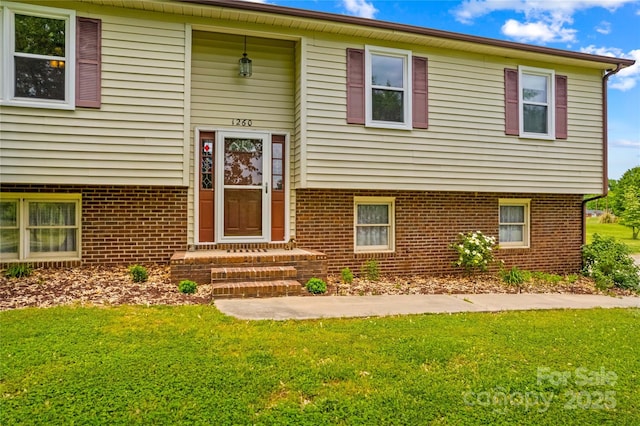 bi-level home with brick siding and a front lawn