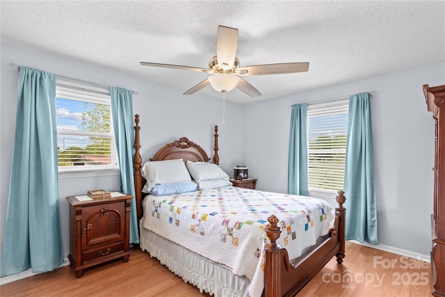 bedroom featuring a textured ceiling, multiple windows, and light wood-style floors