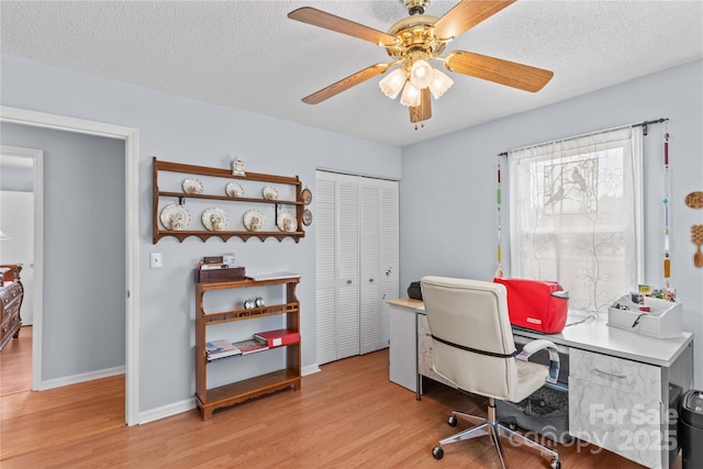 office area with baseboards, a ceiling fan, a textured ceiling, and light wood-style flooring