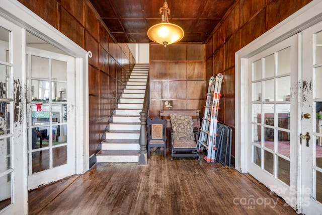 foyer featuring stairs, wood finished floors, and wooden walls