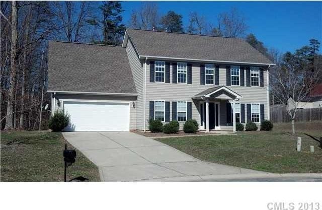 colonial-style house featuring concrete driveway and a front yard