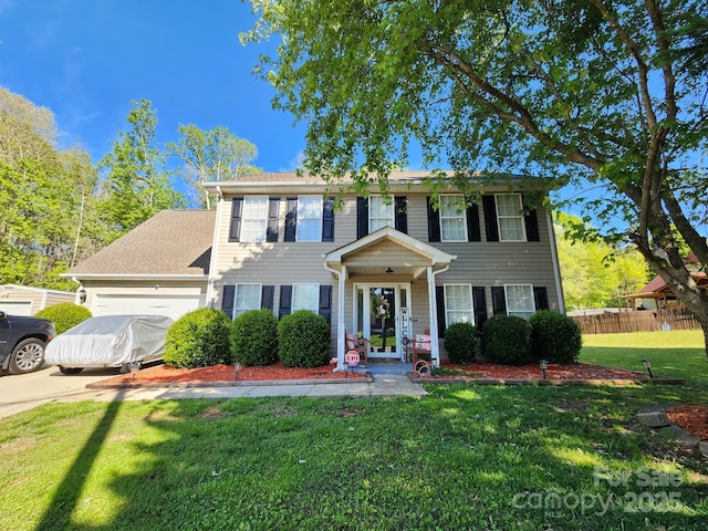 colonial house with fence, a garage, a front lawn, and driveway