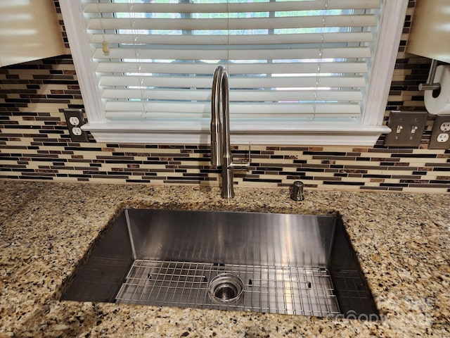 details with stone countertops, backsplash, and a sink