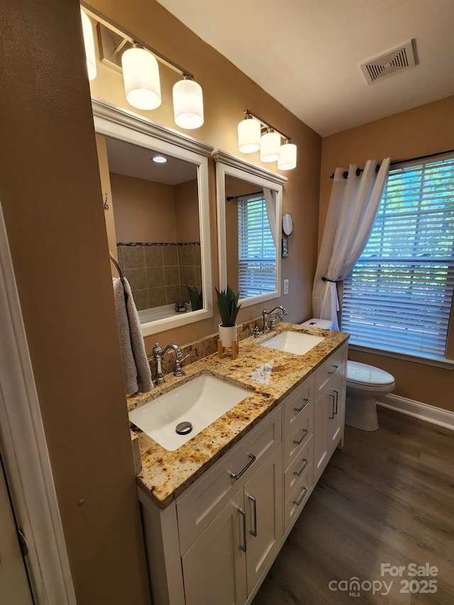 bathroom featuring a sink, toilet, visible vents, and wood finished floors