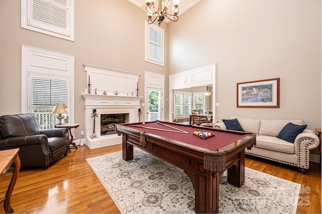 5933 Flintlock Ct, Hickory, NC 28601 - game room with billiards table, a towering ceiling, a fireplace with raised hearth, light wood-type flooring, and a chandelier