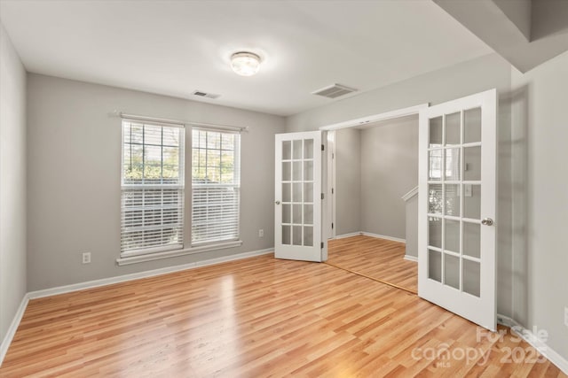 empty room with baseboards, visible vents, french doors, and wood finished floors