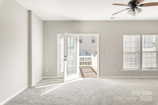 carpeted empty room with baseboards, ceiling fan, visible vents, and a healthy amount of sunlight