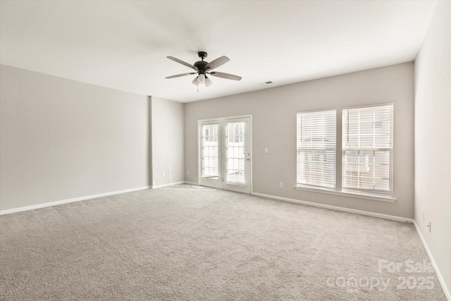 carpeted empty room with baseboards, a ceiling fan, and visible vents