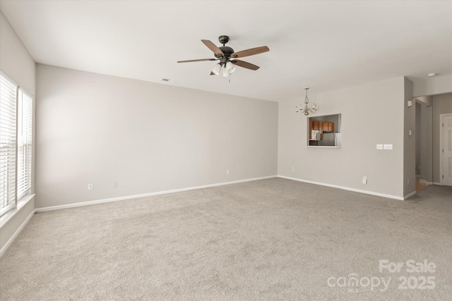 unfurnished living room featuring carpet flooring, ceiling fan with notable chandelier, and a wealth of natural light