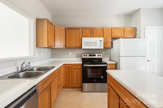 kitchen with a sink, appliances with stainless steel finishes, brown cabinets, and light countertops