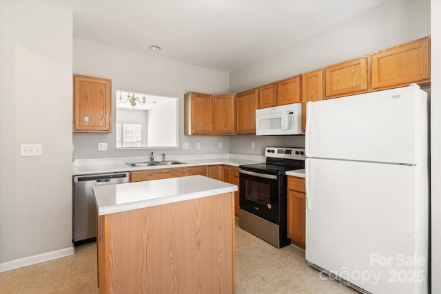 kitchen featuring appliances with stainless steel finishes, a sink, light countertops, a center island, and light floors