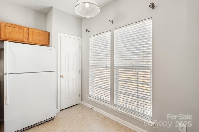 kitchen with baseboards, freestanding refrigerator, and light floors