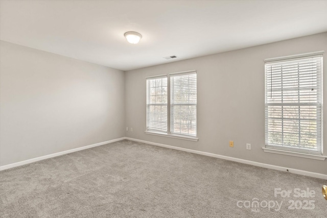 carpeted spare room featuring baseboards and visible vents