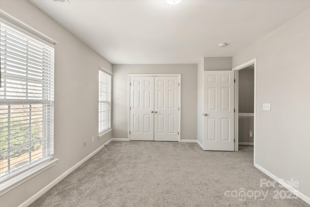 unfurnished bedroom featuring a closet, baseboards, and carpet flooring