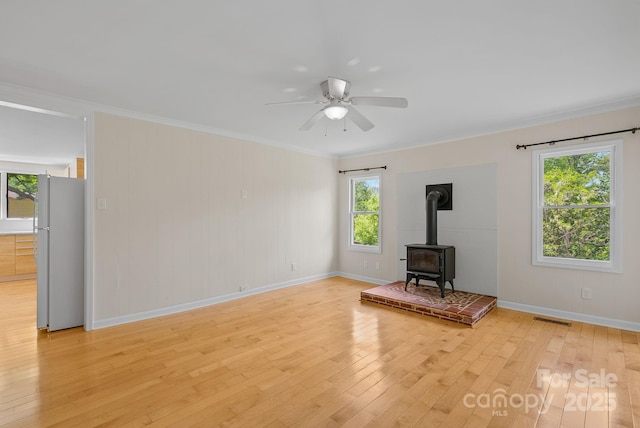 443 Ox Creek Rd, Weaverville, NC 28787 - unfurnished living room featuring a wood stove, light wood-type flooring, baseboards, ornamental molding, and a ceiling fan