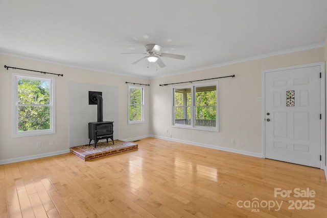 443 Ox Creek Rd, Weaverville, NC 28787 - unfurnished living room featuring a wood stove, healthy amount of natural light, a ceiling fan, light wood-style floors, and crown molding