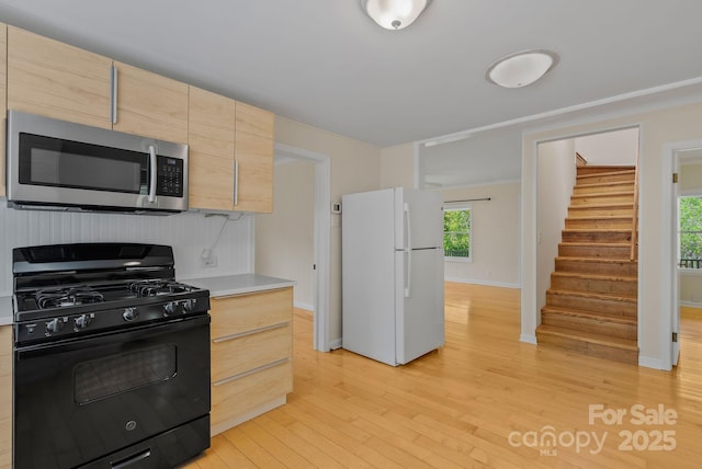 443 Ox Creek Rd, Weaverville, NC 28787 - kitchen featuring stainless steel microwave, freestanding refrigerator, black range with gas stovetop, light brown cabinets, and light countertops
