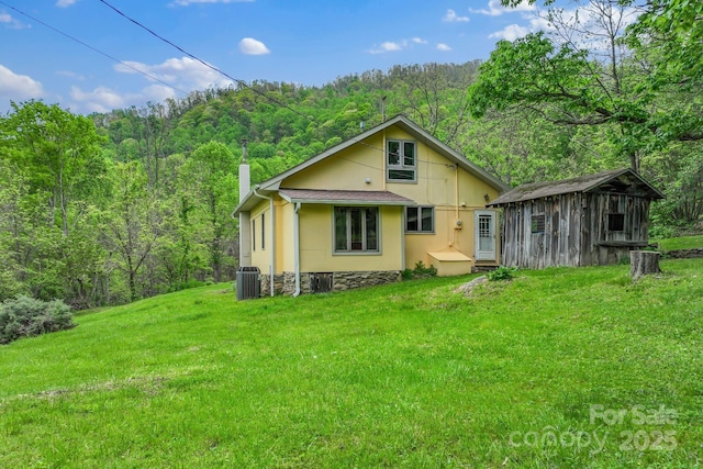 443 Ox Creek Rd, Weaverville, NC 28787 - back of property with a wooded view, central air condition unit, a yard, a chimney, and an outbuilding