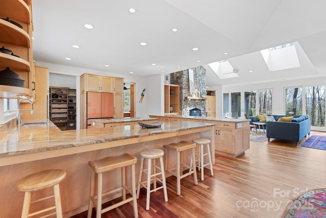 kitchen with light brown cabinetry, built in refrigerator, a skylight, and a sink