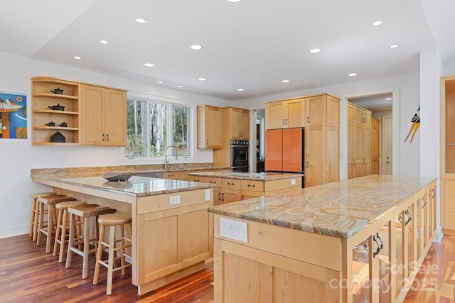 kitchen with light brown cabinetry, a sink, a center island, recessed lighting, and a peninsula