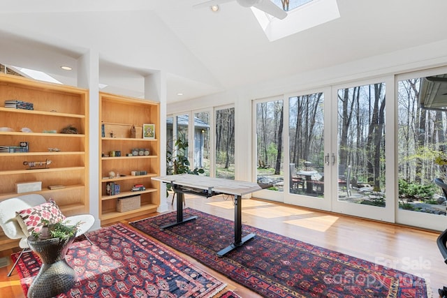 office space featuring vaulted ceiling with skylight, a wall unit AC, recessed lighting, and wood finished floors