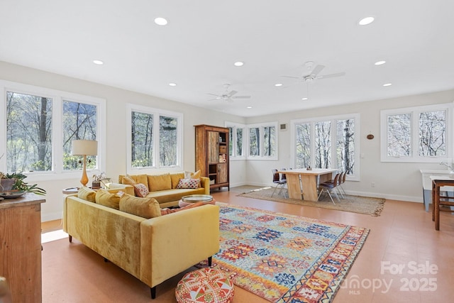 living room featuring baseboards, a ceiling fan, recessed lighting, and a wealth of natural light