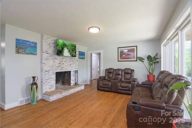 living area with light wood finished floors, a large fireplace, visible vents, and baseboards