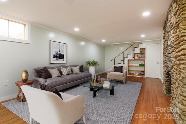 living room featuring wood finished floors, baseboards, ornamental molding, and stairs