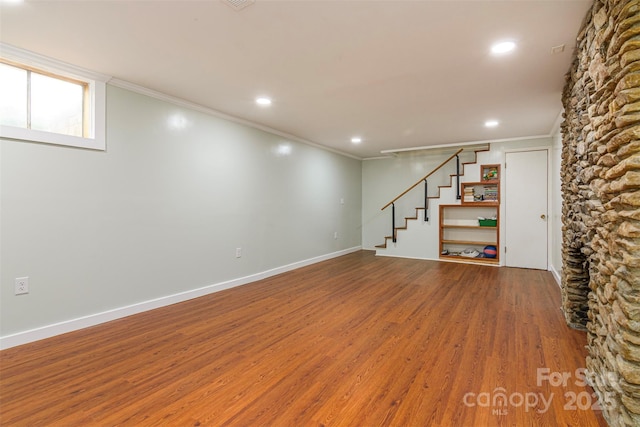 below grade area featuring crown molding, baseboards, recessed lighting, wood finished floors, and stairs