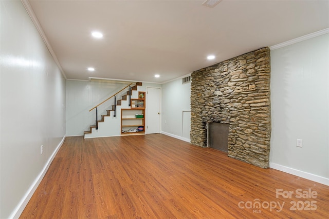 unfurnished living room featuring crown molding, stairway, visible vents, baseboards, and wood finished floors