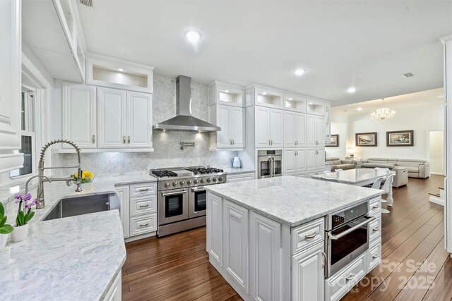 3009 Brooks Mill Ln, Wingate, NC 28174 - kitchen with wall chimney exhaust hood, appliances with stainless steel finishes, a sink, white cabinetry, and tasteful backsplash
