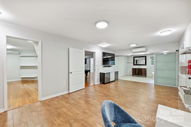 3009 Brooks Mill Ln, Wingate, NC 28174 - unfurnished living room featuring a wall mounted air conditioner, light wood-type flooring, and baseboards