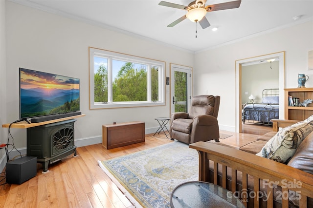 630 Graybeal Holw, Creston, NC 28615 - living room featuring light wood-style floors, a wood stove, a ceiling fan, crown molding, and baseboards