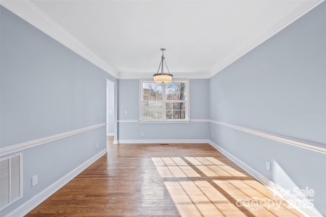 unfurnished dining area featuring visible vents, baseboards, crown molding, and wood finished floors