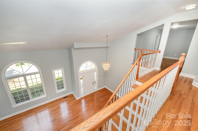 entrance foyer with baseboards, vaulted ceiling, plenty of natural light, and light wood-style floors