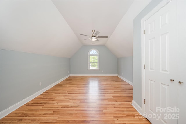 additional living space featuring a ceiling fan, baseboards, vaulted ceiling, and light wood-style floors