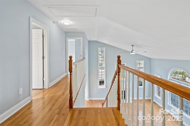 corridor with attic access, an upstairs landing, wood finished floors, baseboards, and lofted ceiling