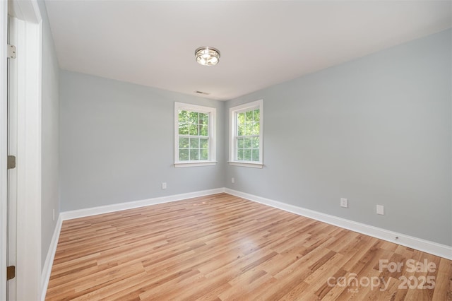 empty room featuring baseboards and light wood finished floors