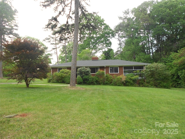 single story home with a chimney, brick siding, and a front lawn