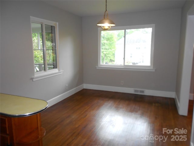 unfurnished dining area with wood finished floors, visible vents, and baseboards