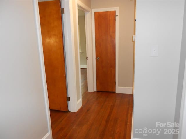 hallway with baseboards and wood finished floors