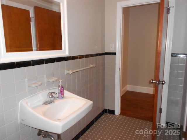 bathroom featuring tile walls, a wainscoted wall, and a sink