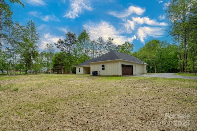 view of side of property featuring a lawn, driveway, cooling unit, and a garage