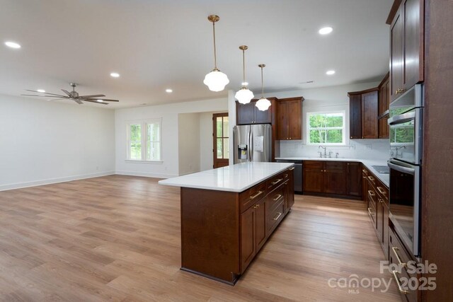 kitchen featuring light countertops, appliances with stainless steel finishes, a wealth of natural light, and a center island