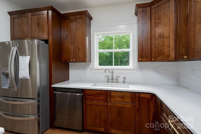 kitchen with a sink, light countertops, decorative backsplash, and stainless steel appliances